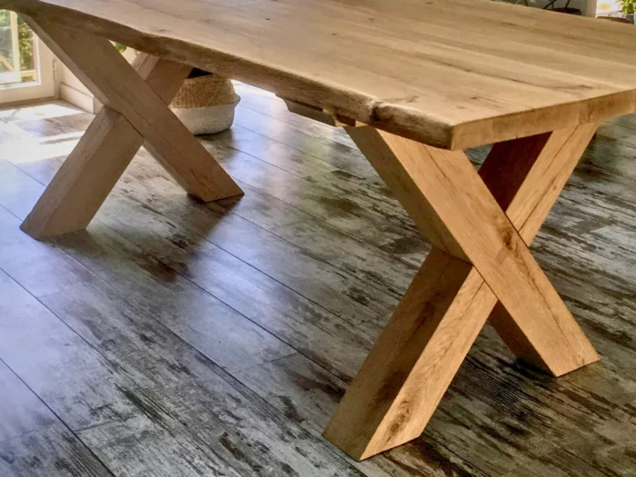 Un salon avec une table, doté d'un pied de table Croix en bois massif
