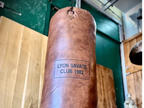 Un sac de boxe vintage avec l'inscription "Lyon savate club 1982"