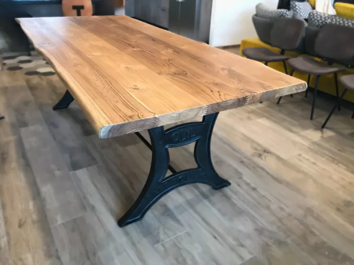 Une table à manger dans un salon, avec un pied en fonte Café de Lyon