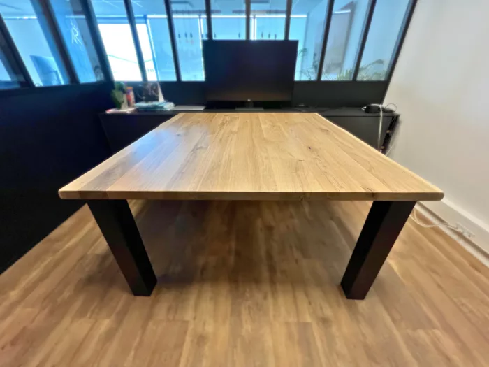 Une table dans un bureau avec des pieds carrés en acier noir