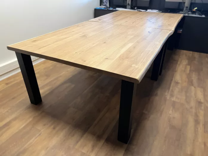 Une table en chêne clair avec une rallonge, avec des pieds des table carrés en acier