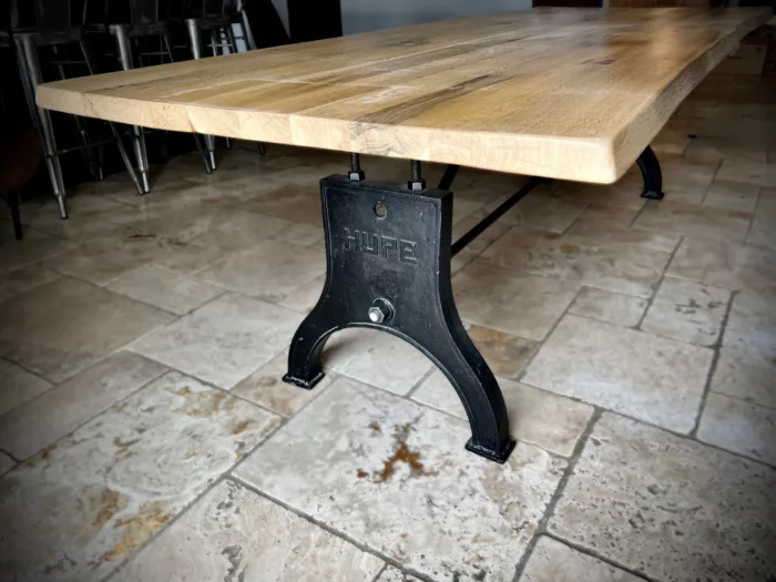 Une table avec un plateau en chêne clair et des pieds de table en fonte, dans un style industriel