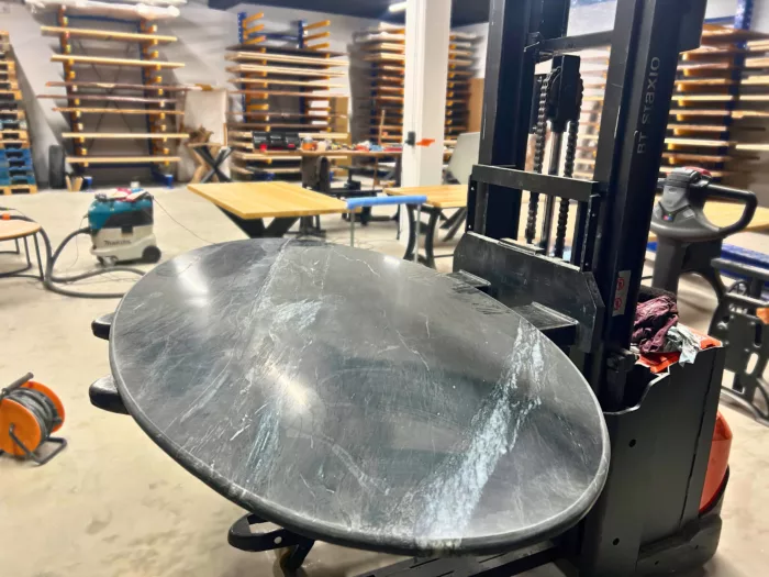 Un plateau de table oval en marbre noir dans un atelier