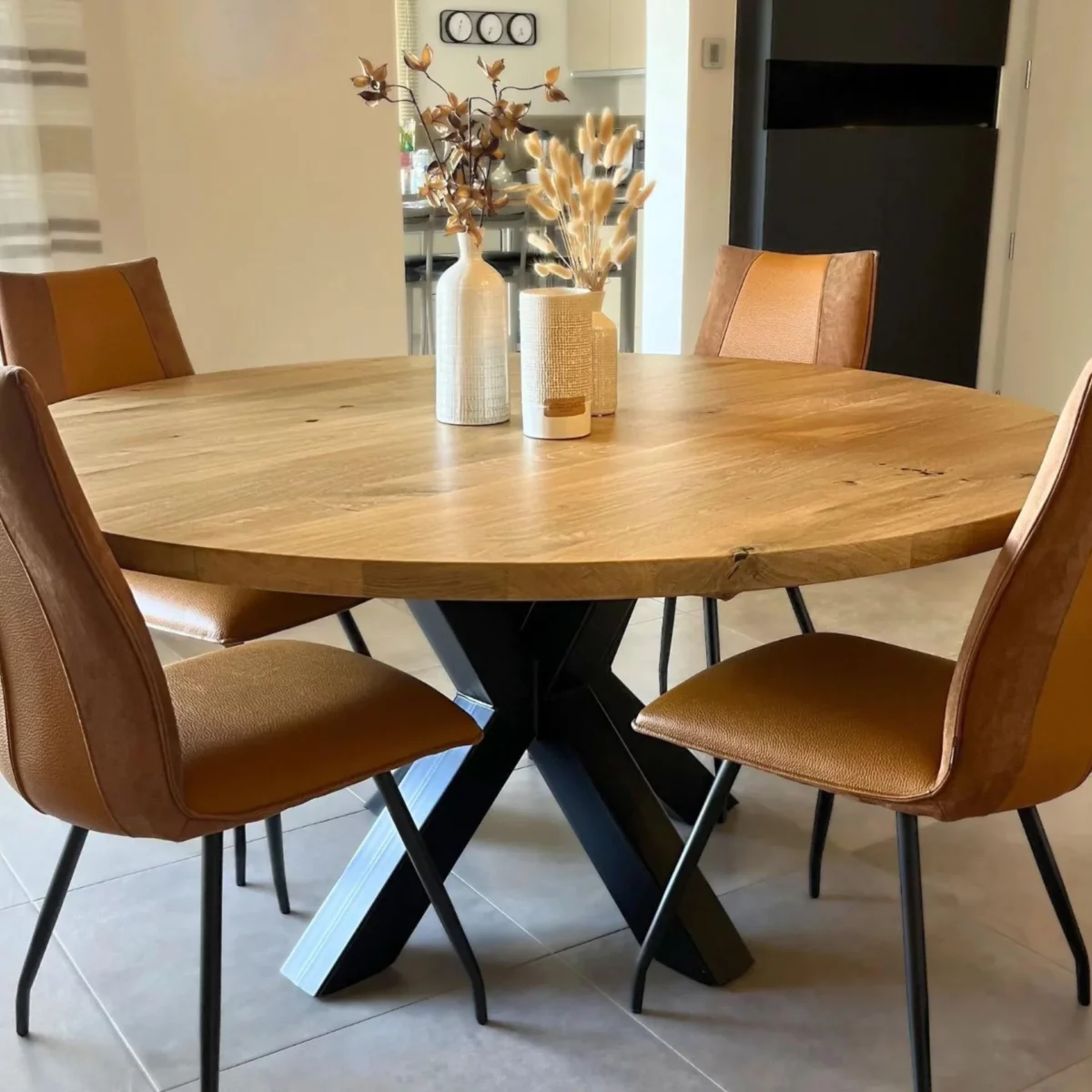 Un salon avec une table à manger ronde et un pied central, et quatre chaises marron