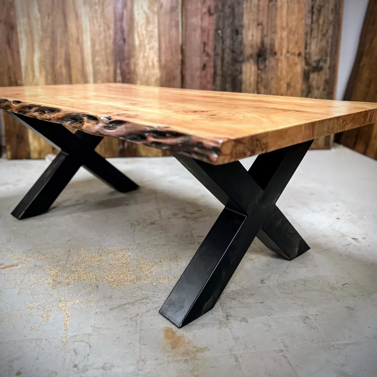 Une table basse avec des pieds en acier noir en croix