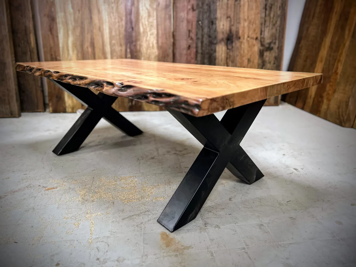 Une table basse avec des pieds en acier noir en croix