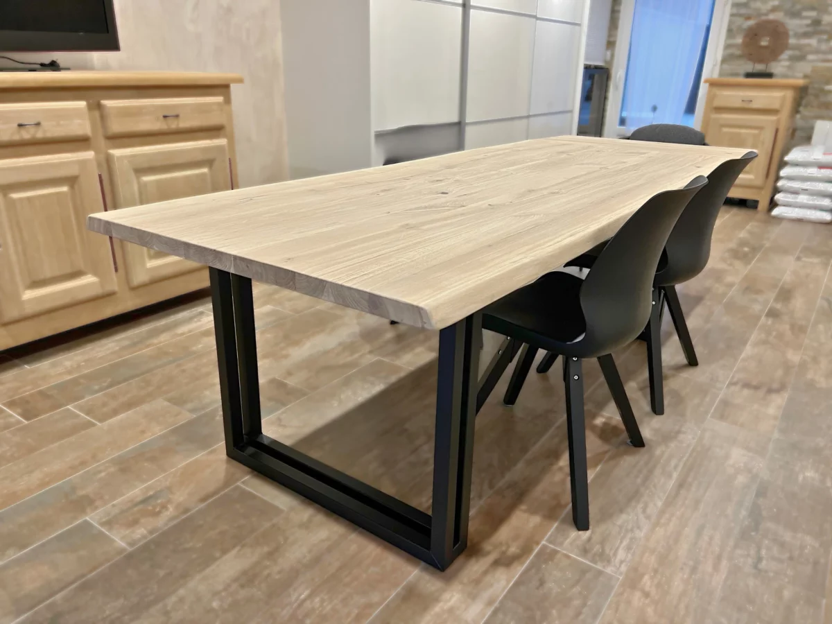 Une table à manger en bois et métal avec des chaises noires