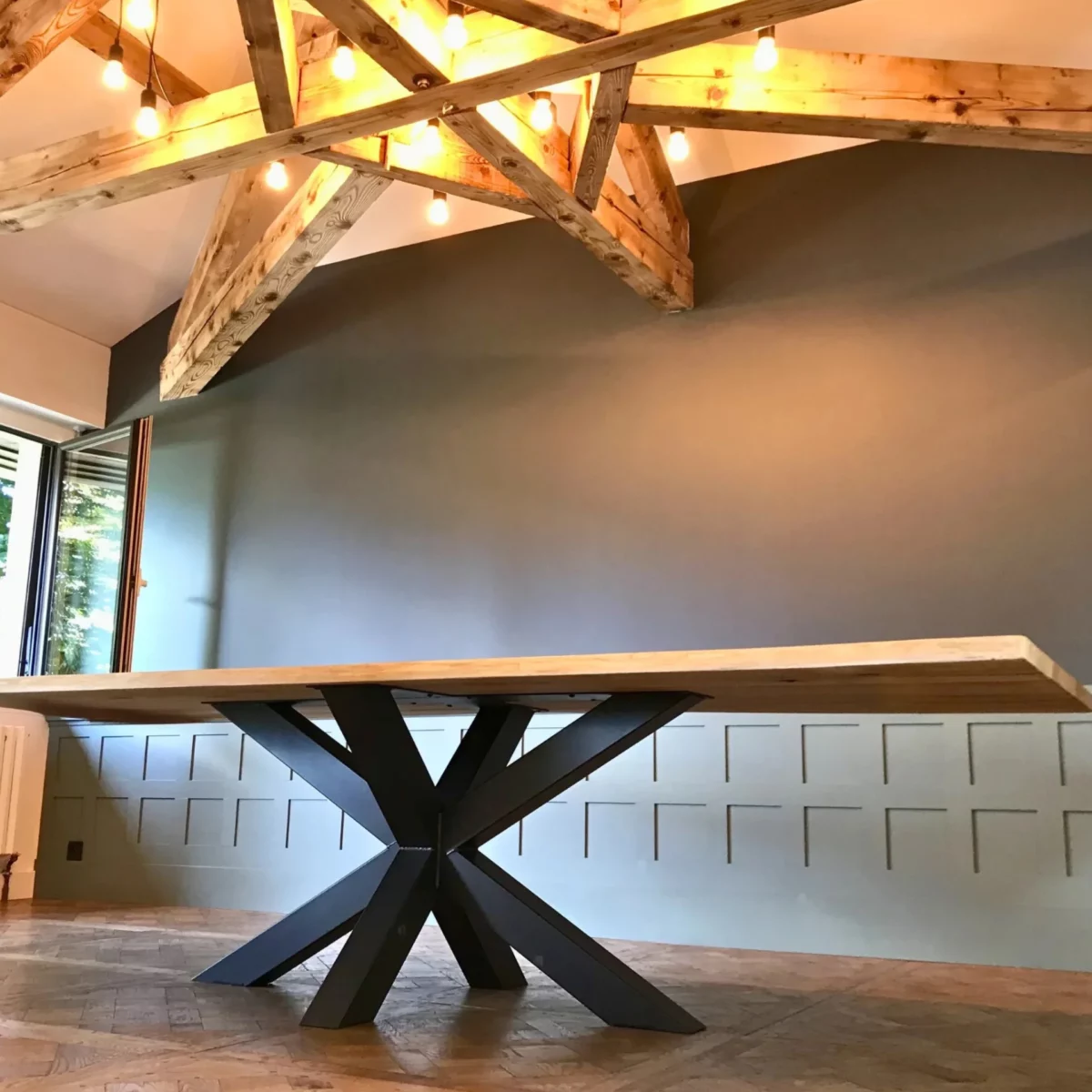 Un grand salon avec un table en bois massif, avec un pied Etoile central acier robuste