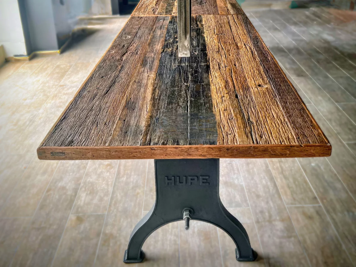 Une table à manger, avec un pied en fonte et un plateau en bois recyclé