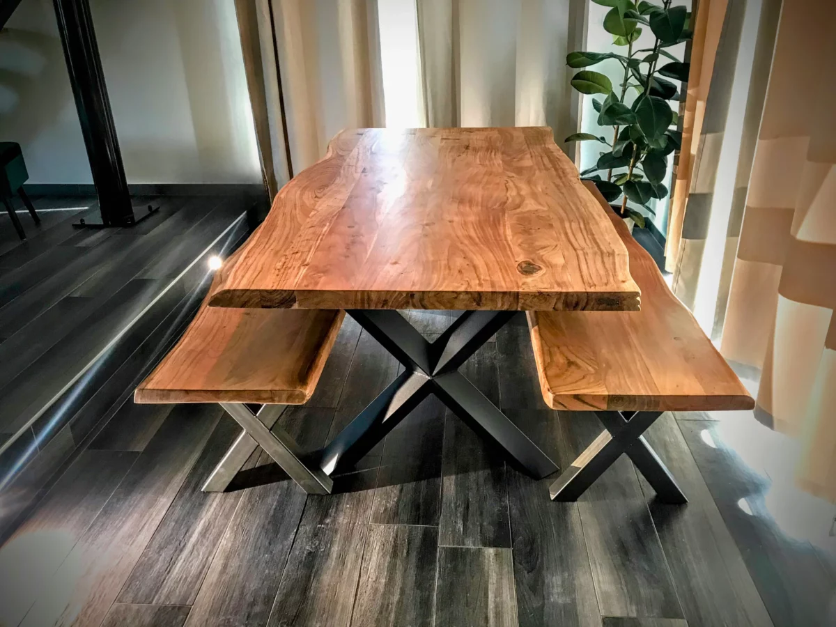 Une table à manger avec des pieds croisés, avec deux bancs avec des pieds croisés